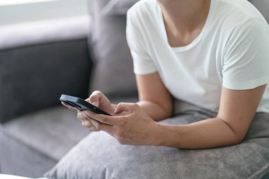 Sosyal medyayı kontrol etmek için akıllı telefon kullanan ya da ekranda kitap okuyan bir kadın.