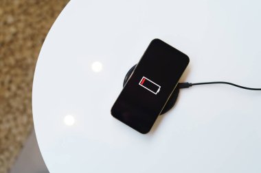 Charging mobile phone battery with wireless charging device in the table. Smartphone charging on a charging pad. Mobile phone near wireless charger Modern lifestyle technology concept