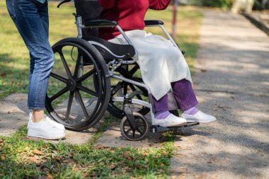 Huzurevi. Genç bakıcı tekerlekli sandalyedeki yaşlı kadına yardım ediyor.