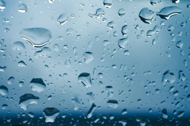 Pencere camlarına güneş batarken yağmur damlaları düşer. koyu metin seçici odak için pencere arkaplanındaki cam sprey üzerine damlalar