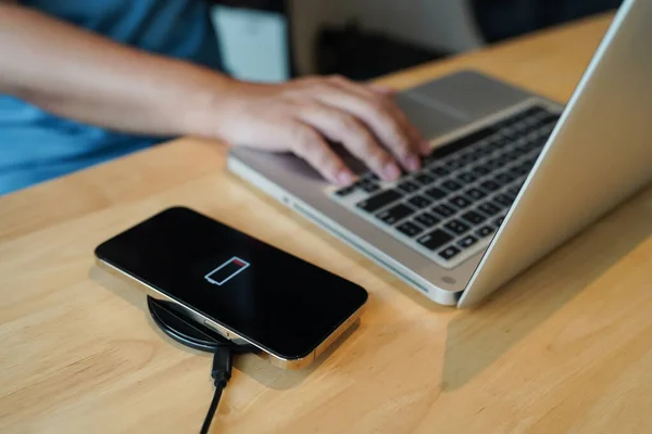 stock image Charging mobile phone battery with wireless charging device in the table. Smartphone charging on a charging pad. Mobile phone near wireless charger Modern lifestyle technology concept.