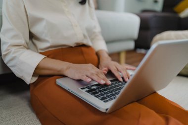 Ahşap masada dizüstü bilgisayar kullanarak çalışıyor. Eller bir klavyeye basıyor. Teknoloji e-ticaret konsepti..