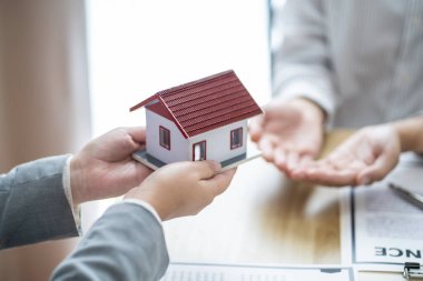 Sales manager giving advice application form document, considering mortgage loan offer for car and house insurance. Real estate investment Property insurance and security. Real estate agent offer house