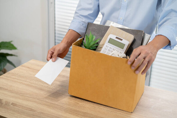 sending resignation letter to boss and Holding Stuff Resign Depress or carrying cardboard box by desk in office.