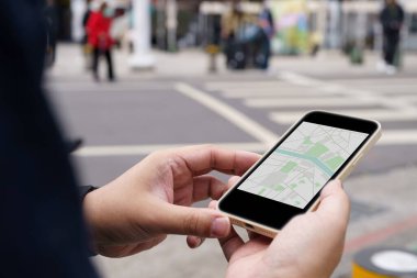 Şehir merkezinde bagaj taşıyan bir kadın harita uygulamasında GPS kullanarak arama yapıyor.