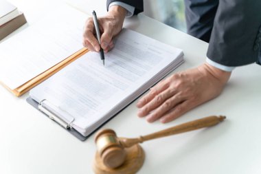 Avukat hukuk danışmanı müvekkiline tokmak ve hukuk hukuku ile imzalanmış bir sözleşme sunar. Adalet ve Avukat İş ortaklığı toplantısı