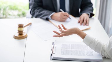 Avukat hukuk danışmanı müvekkiline tokmak ve hukuk hukuku ile imzalanmış bir sözleşme sunar. Adalet ve Avukat İş ortaklığı toplantısı