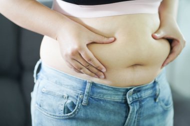 Şişman kadın karnı için üzülüyor. Kilolu bir kadın şişman karnına dokunuyor ve kilo vermek istiyor. Dar elbiseli şişman kadın kilo diyeti yaşam tarzı konsepti hakkında endişeli..