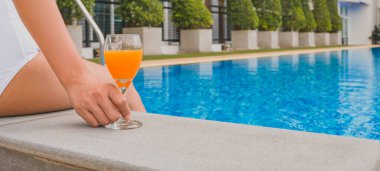 Yaz tatili genç Asyalı güzel kadın spa merkezinde havuzda dinleniyor. Yüzme havuzundaki güzel tropikal plaj oteli