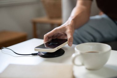 Charging mobile phone battery with wireless charging device in the table. Smartphone charging on a charging pad. Mobile phone near wireless charger Modern lifestyle technology concept