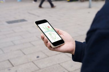 Şehir merkezinde bagaj taşıyan bir kadın harita uygulamasında GPS kullanarak arama yapıyor.