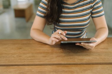 Elinde dijital tablet aygıtı ya da sosyal medya uygulamaları hakkında e-kitap okuyan bir kitap aygıtı tutan kadın
