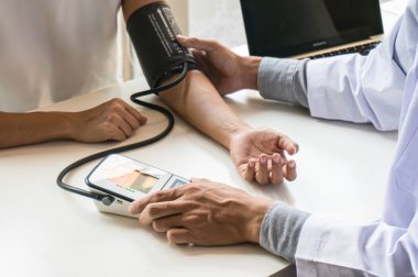 Doktor Sağlık Hizmetleri. Beyaz üniformalı profesyonel tıp doktoru hastasına danışmanlık yapıyor ve erkek hastasına yardım ediyor. 