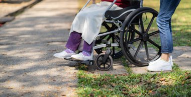 Huzurevi. Genç bakıcı tekerlekli sandalyedeki yaşlı kadına yardım ediyor.