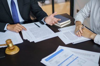 Avukat hukuk danışmanı müvekkiline tokmak ve hukuk hukuku ile imzalanmış bir sözleşme sunar. Adalet ve Avukat İş ortaklığı toplantısı konsepti