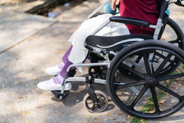 Huzurevi. Genç bakıcı tekerlekli sandalyedeki yaşlı kadına yardım ediyor.