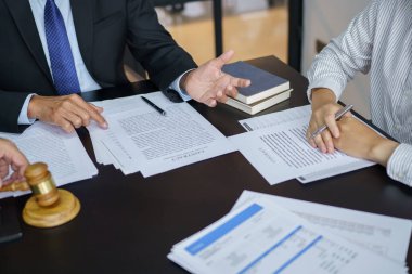 Avukat hukuk danışmanı müvekkiline tokmak ve hukuk hukuku ile imzalanmış bir sözleşme sunar. Adalet ve Avukat İş ortaklığı toplantısı konsepti