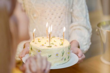 Cheerful friends enjoying home Birthday holiday party. Asian sister cheering drinking red wine celebrating with Birthday cake