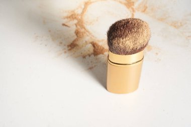 Yumuşak kozmetik fırçası, tüyleri ışıl ışıl parlıyor. Toz masanın üzerine saçılmış. Güzellik ve makyaj konseptini kopyalamak için geniş bir arkaplan üzerine.
