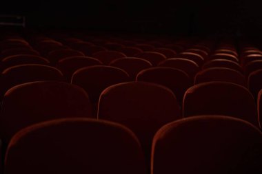 Fotokopi alanı olan karanlık boş sinema salonundaki turuncu, kırmızı koltukları kapatın. Seçici odaklı sıra sıra sandalyelerle arka plan. Etkinlik kavramı, tiyatro, konferans, gösteri, sunum, seyirci.
