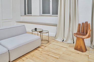 Kanepenin bir kısmının yakın çekimi ve modern bir oturma odasının içinde el şeklinde bir sandalye. Kopyalanacak çok az mobilya var. Yüksek kalite fotoğraf