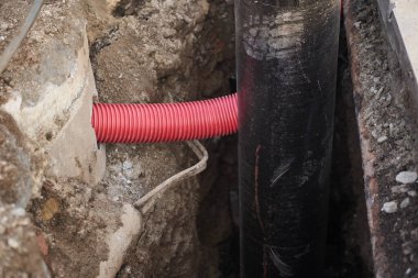 Yeraltındaki kablolardan oluşan yalıtım kablosu, plastik borular, su için yalıtım malzemesi olan büyük siyah boru, kopyalama alanı olan kırmızı kıvrım borusu. Yeraltı işleri, kablolar ve iletişim.