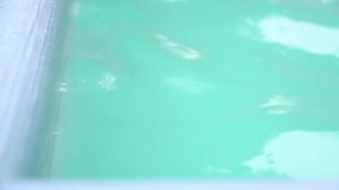 Havuzdaki mavi suyun yüzeyi dalgalarla hareket ediyor. Havuzun bir kısmı suyun hareketinde. Yüksek kalite 4k görüntü