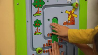Duvarda ahşap labirent oynayan iki çocuğun ellerinin yakın çekimi. Çocuklar için eğitici mantık oyuncakları. Yüksek kalite 4k görüntü