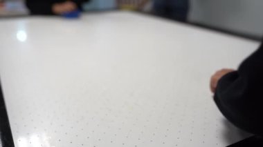 Hava hokeyi masasına odaklan. İki arkadaş bir hava hokeyi maçında yarışıyor. Çamaşır makinesiyle bir elin yakın çekimi. Yüksek kalite 4k görüntü