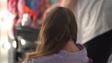 Usta saçı iki parçaya ayırdı ve bir parçasını at kuyruğuna koydu. Pembe kanekalondan örgü örmeye hazırlık. Yüksek kalite 4k görüntü