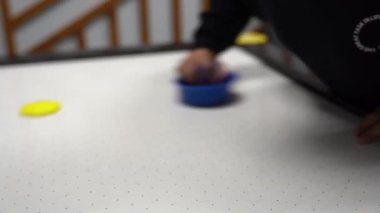 Hava hokeyi masasına odaklan. Bir çocuk rakibiyle hava hokeyi oynuyor. Masada çamaşır makinesiyle bir elin yakın çekimi. Yüksek kalite 4k görüntü