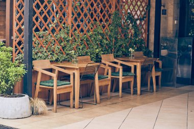 Ahşap masası ve sandalyesi olan boş bir kafe terası. Çiçekleri ve masası olan rahat bir cadde, kopyalayacak yeri olan ön cephe dekorasyonu. Yüksek kalite fotoğraf
