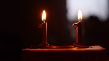 Karanlıkta, bir çocuk doğum günü pastasının üzerindeki mumları 11 numarayla üflüyor. Doğum günü kutlaması. Mumların üzerindeki ateş sönüyor. Yüksek kalite 4k görüntü