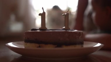 11 numaralı doğum günü pastası tabakta. Mumları yakmak için bekliyorum. Doğum günü kutlaması. Çocuksu bir yüzü olan bulanık bir arka plan. Yüksek kalite 4k görüntü