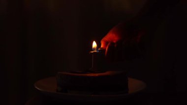 Koyu bir arka planda, 1 numaralı tabakta bir doğum günü pastası. Mum koyu bir arka planda yanıp sönüyor. Mumu üflüyorum. Yüksek kalite 4k görüntü