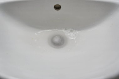 Seramik banyo lavabosunun en üst görüntüsü. Su kanalizasyona akıyor. Kopyalayacak yer de var. Yüksek kalite fotoğraf