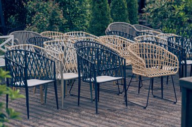 Açık havada plastikten yapılmış hasır sandalyeler var, arka planda yeşil çalılar var. Kafe kapalı, sabahleyin hiç ziyaretçi olmaz. Kopyalayacak yer de var. Yüksek kalite fotoğraf