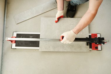 Ustanın bir makineyle fayansı iki parçaya ayırdığı yakın plan. Büyük seramik fayansları kesin boyutları olan daha küçük fayanslara kesen bir makine. Yüksek kalite fotoğraf