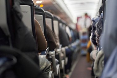 Uçakta yiyecek ve içecek dağıtan bir erkek kahyanın bulanık görüntüsü. Yolcular koltuklarında oturup izliyorlar. Sıranın sonuna bak. Yüksek kalite fotoğraf