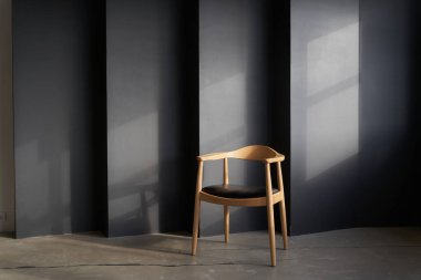 Yuvarlak şekilli ve tasarımı karanlık bir duvarın karşısında duran tahta bir sandalye. Kopyalama alanı siyah düz olmayan duvarda siyah ile işaretlenmiş. Yüksek kalite fotoğraf