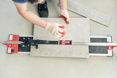 Büyük seramik fayansları kesin boyutlarla daha küçük fayanslara kesmek için bir kurulum. Ustanın bir makineyle fayansı iki parçaya ayırdığı yakın plan. Yüksek kalite fotoğraf