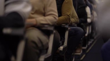 Koltuklarında oturan ve izleyen yolcuların koltukları boyunca bakın. Tanınmayan insanlar uçağın kalkmasını bekliyorlar. Yüksek kalite 4k görüntü