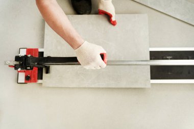 Ustanın bir makineyle fayansı iki parçaya ayırdığı yakın plan. Büyük seramik fayansları kesin boyutları olan daha küçük fayanslara kesen bir makine. Yüksek kalite fotoğraf