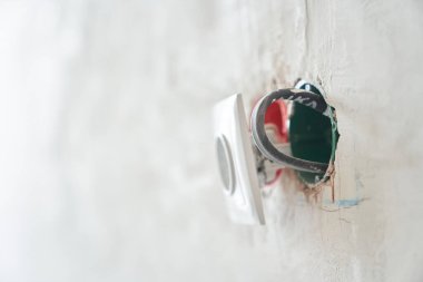Dairenin duvarına elektrik kabloları takılı bitmemiş bir elektrik prizi. Yüksek kalite fotoğraf