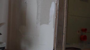 Macunu bir spatulaya dağıt. Ev tadilatı. Daire tadilatı. Ellerinde inşaat metali spatulası olan erkekler koruyucu eldivenler giyer. Yüksek kalite 4k görüntü