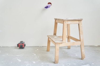 Lazer teçhizatının yanında ahşap bir tezgah. Elektrik prizi tamamlanmamış, kablolar mor elektrik bandıyla sarılmış. Kopyalanacak bir yer var. Yüksek kalite fotoğraf