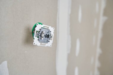 Priz kurulumuna hazırlanılıyor. Elektrik kablolarıyla dolu bir bağlantı kutusu. Arka plan alçıpandan yapılmış, alçıdan çatlaklar ve kopyalamak için bir alan var. Yüksek kalite fotoğraf