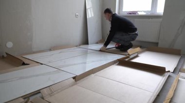 Adam şablonu düzenlemek için fayansları dizer. Duvarlara 120 'ye 60 boyutlarında geniş formatlı porselen döşeme. Yüksek kalite 4k görüntü