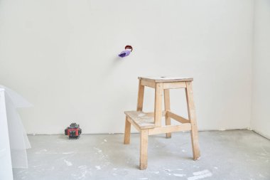 Beton duvarın arka planında lazer aletlerinin yanında ahşap bir tezgah var. Elektrik prizi tamamlanmamış, kablolar mor elektrik bandıyla sarılmış. Yüksek kalite fotoğraf