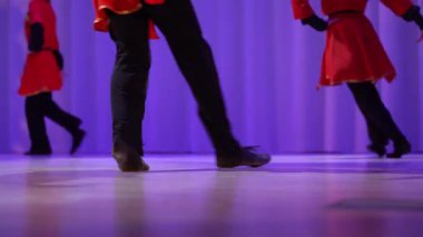 Tanınmayan dansçılar Kazak dansı yapıyorlar. Sahnedeki dansçıların bacaklarına yakın çekim. Sahnede gösteri. Yüksek kalite 4k görüntü